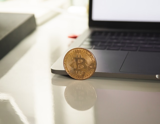 Bitcoin resting against the side of a laptop